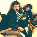 Taken from above, indoor portrait of four-piece Tropical Fuck Storm seated in a neutrally coloured room.