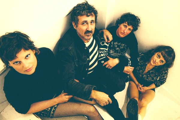 Taken from above, indoor portrait of four-piece Tropical Fuck Storm seated in a neutrally coloured room.