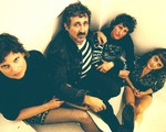 Taken from above, indoor portrait of four-piece Tropical Fuck Storm seated in a neutrally coloured room.