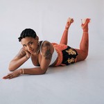 Studio portrait of Yaya Bey laying down on her stomach, gazing toward the camera.