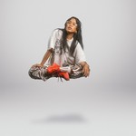 Solo artist Kimmortal is levitating, with legs crossed, in front of a blank background.