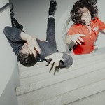 Experimental action shot of duo Xiu Xiu lying down on a set of stairs, with arms extended