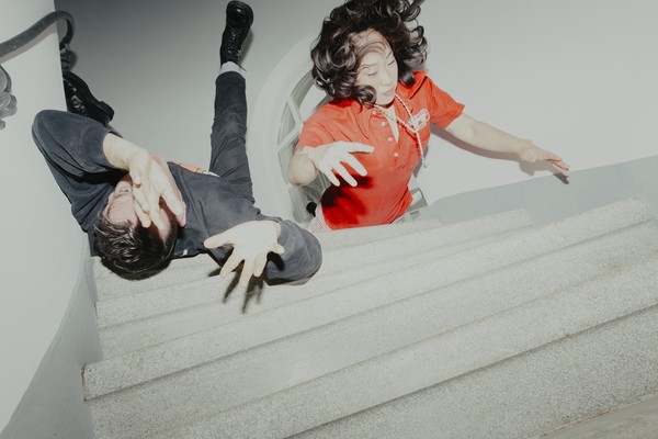 Experimental action shot of duo Xiu Xiu lying down on a set of stairs, with arms extended