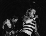 Black and white action shot of the vocalist and guitarist of Sn​õ​õ​per energetically performing on a stage.
