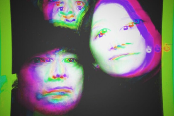 A distorted photo shows three-piece band DMBQ with their heads pushed with a purple and green colour effect on top. 