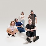 Studio portrait of five-piece 4BPM. Three members are seated and two are standing, all smiling toward the camera.