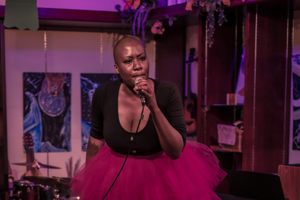 Portrait of solo artist A.N singing into a microphone, performing at Alcove Music & Arts Centre.