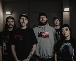Dark, gritty portrait of five-piece Abrupt Decay standing and looking toward the camera.