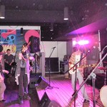 Photo of act ADOPTION peforming with a guitar on stage, in front of an engaged audience.