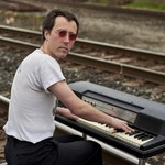 Avalon Tassonyi is playing an antique keyboard on a traintrack, looking toward the camera