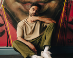 Solo artist Bijaan is sitting against a large outdoor street painting.