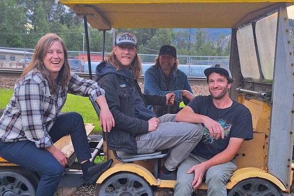 Four members of BITTER//WASHED are seated in a yellow golf cart.