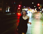 Photo taken at night of Michele ii Visser of Boniface walking down a major road with streetlights and carlights lighting the background.