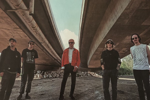 Photo of five-piece Bridgeland standing underneath a bridge by the river.