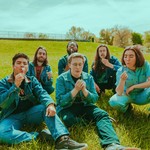 Outdoor photo taken on a field on a sunny day, featuring seven members of DOOM GONG blowing dandelions while dressed in matching denim