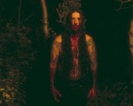 Dark outdoor photo featuring a member of ECHTHROS with long dark hair, covered in blood on their hands, mouth and chest.