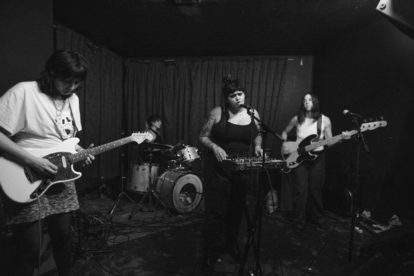 Black and white photo of four-piece Eraser performing on stage with a guitar, bass, keyboard and drums