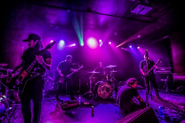 A colour photo shows five-piece band Everythingyoueverloved on a stage lit with purple lights .