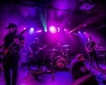 A colour photo shows five-piece band Everythingyoueverloved on a stage lit with purple lights .