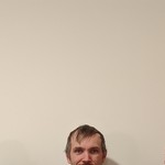 A colour photo shows three-piece band Fulfilment standing in a line against a beige wall. Each member is only shown from the nose up at the bottom of the frame.
