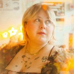 A colour photo with a lens flare effect features a close-up of artist Future Star, sitting in a room looking to their left.