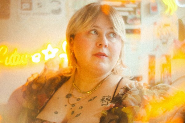A colour photo with a lens flare effect features a close-up of artist Future Star, sitting in a room looking to their left.