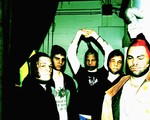 An over exposed colour photo shows the five-piece band Hillboro standing in a room all with pantyhose over their faces.