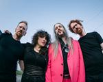 A colour fisheye photo taken from below shows four-piece band lushclot standing outside with a blue sky behind them.