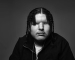 A black and white up-close portrait photo of blind trap artist Mattmac against a grey background.