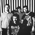 A black and white photo shows four-piece band Pnoon standing in front a black and white striped wall.