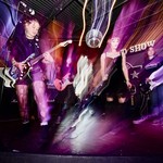 A long exposure colour photo shows five-piece punk band Rebel Grrrlz playing on stage at the Ship and Anchor.