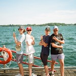 A colour photo shows four-piece band Sea of Lettuce standing on a wooden dock with a body of water behind them. 