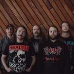 A colour photo of five-piece band Snakepit posing for a photo standing in front of an wall with angled wooden planks.