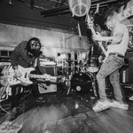 A black and white photo shows three-piece Tebby & the Heavy playing on stage at the Ship and Anchor.