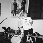 Solo artist The Furnace is shown in black and white singing into a microphone standing next to a drumkit.