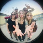 A colour fisheye photo of five-piece band The Radiation Flowers standing in a motel parking lot.