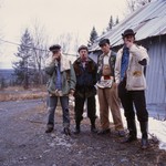 A colour photo shows four-piece group Truck Violence standing outside in front of an old building. Each member is shown smoking a cigarette. 