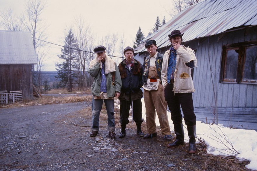 A colour photo shows four-piece group Truck Violence standing outside in front of an old building. Each member is shown smoking a cigarette. 