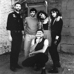 A black and white photo shows five-piece band Uncanny Valley posing in a back alley.