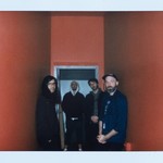 A blurry photo shows four-piece group water margin standing in an orange hallway