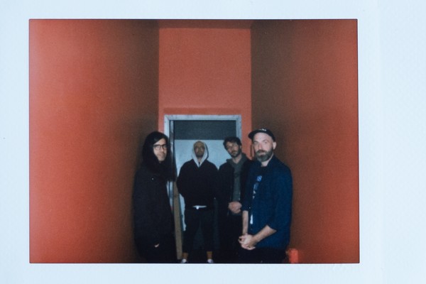 A blurry photo shows four-piece group water margin standing in an orange hallway