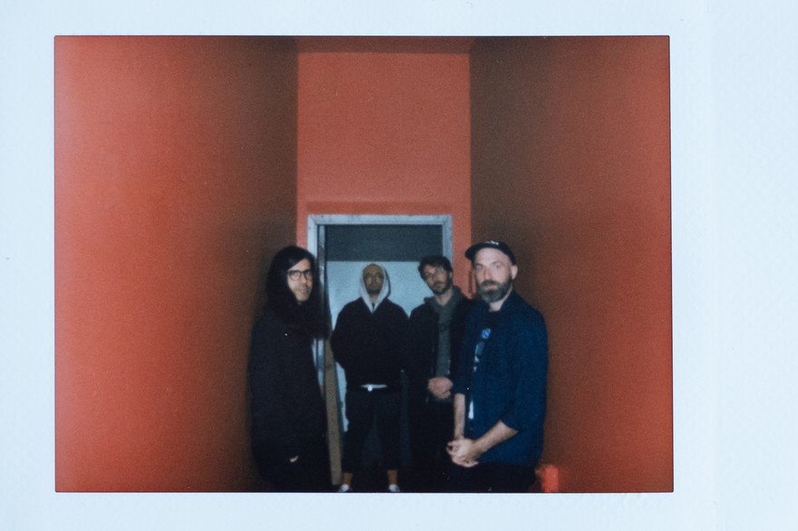 A blurry photo shows four-piece group water margin standing in an orange hallway
