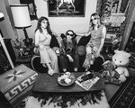 A black and white photo shows the three-piece band Window Lamp Corp posing on a couch