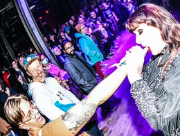 Drag performer Karla Marx is shown performing a crowd at the 2023 Kick-Off Party with an attendee's finger in her mouth