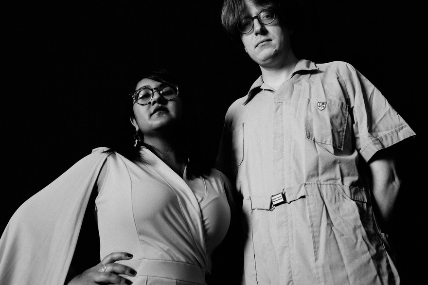 A black and white photo shows duo Sweeping Promises from the waist up taken from below.