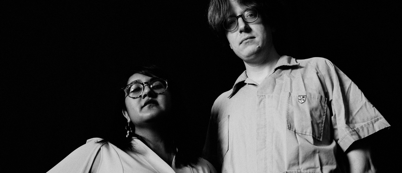 A black and white photo shows duo Sweeping Promises from the waist up taken from below.