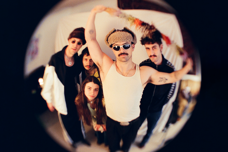 Shot with a fish eye effect, photo of five-piece Pastel Blank posed in a room, facing the camera.