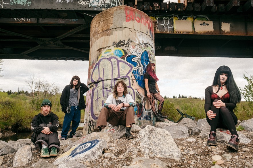 Photo taken outdoors, under a graffiti-filled bridge of five-piece Rebel Grrrlz