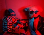 Double exposure photo washed in red light of the front person of Wheelchair Sports Camp holding someone in a leather jacket and sunglasses by the leash