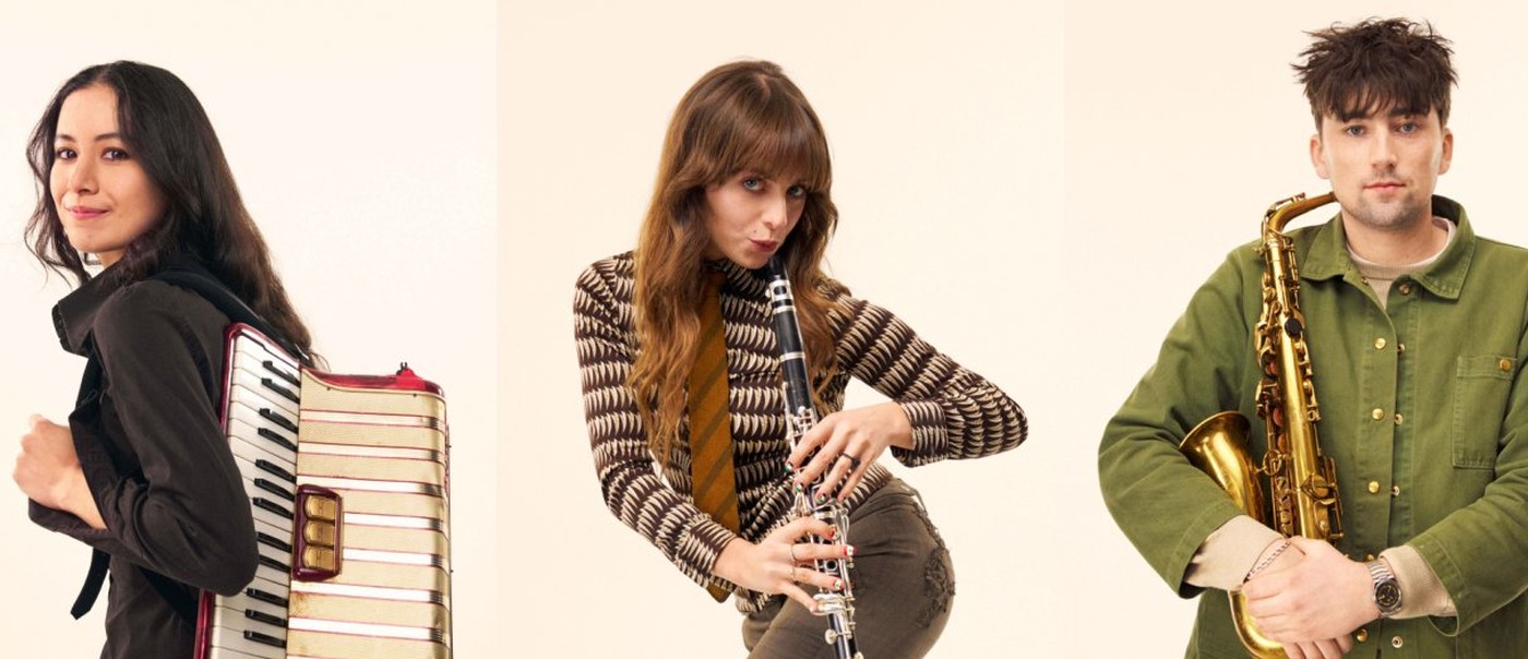 Black Country, New Road in a 3×2 grid of portraits, each holding their instrument against a pale studio backdrop. Their neutral expressions and simple staging give the image a quiet, art‑school formality reminiscent of Black Country, New Road’s visual style.